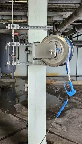 High-pressure stainless steel hose reel and trigger gun mounted to a support column as part of the washdown system at an industrial site in Burton.